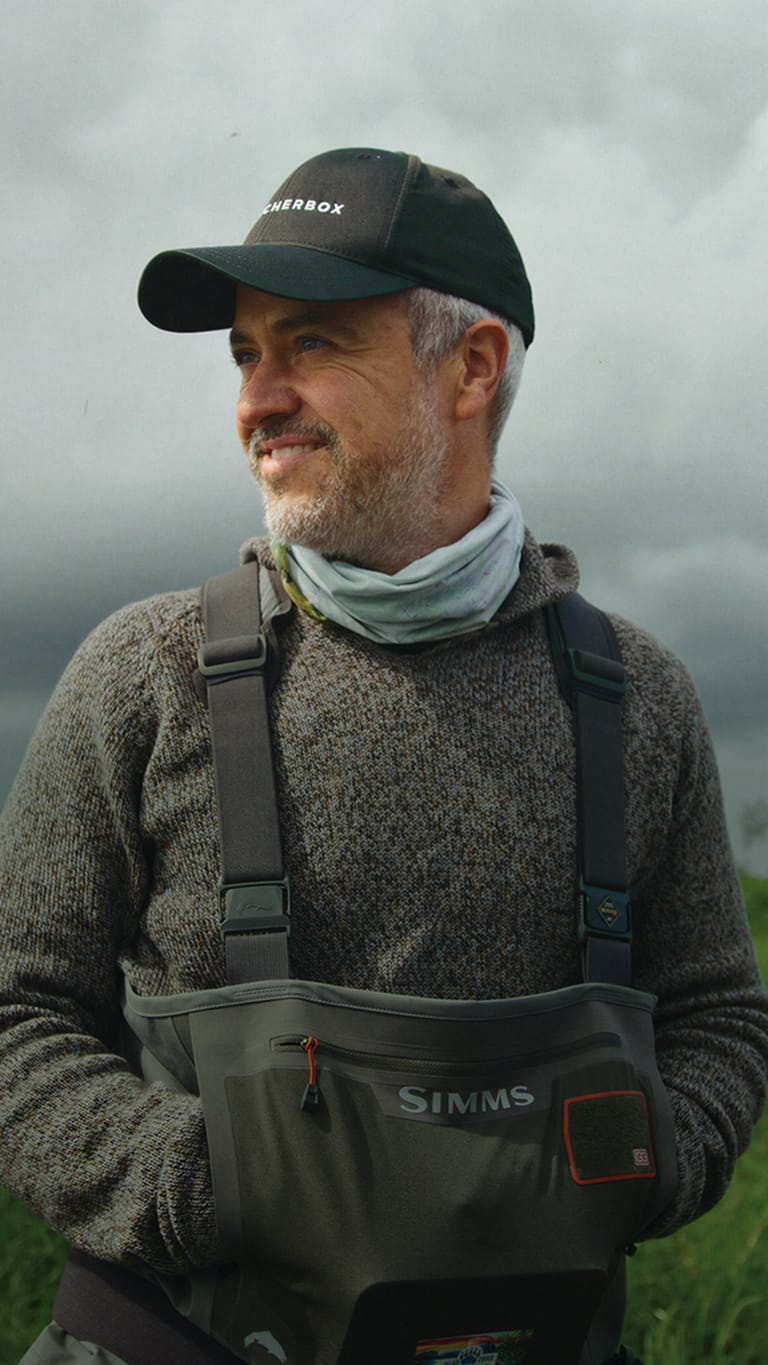 ButcherBox founder Mike Salguero outdoors in a field, wearing a ButcherBox cap