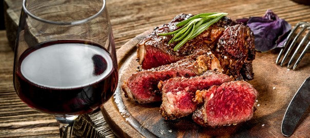 Wine with Steak Grilled ribeye beef steak with red wine, herbs and spices on wooden table